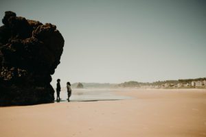 kids in shadow of large beach rock