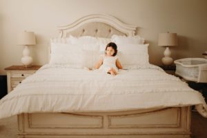 Little girl on all white bed