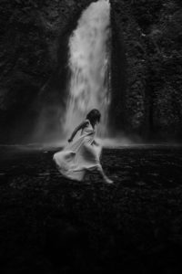 woman walking in front of waterfall