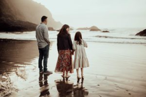Family of three walking toward the ocean