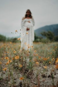 Pregnant woman blurred with flowers in foreground