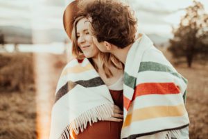 Couple wrapped in blanket kissing on cheek