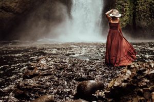 Woman in hat in front of waterfall