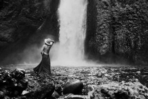 Woman with hat in front of waterfall