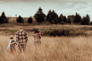 Family of four walking away through tall grass