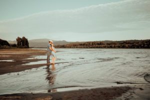 Expecting couple with cowboy hat in shallow water