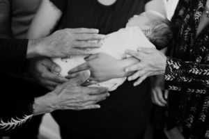 Generations of hands holding baby