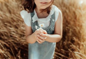 Little girl holding daisies
