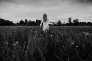 black and white image of girl in daisy field