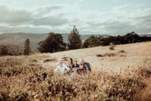 Family sitting in a field of grass in front of mountains