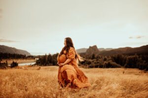 Pregnant woman in field with blowing hair