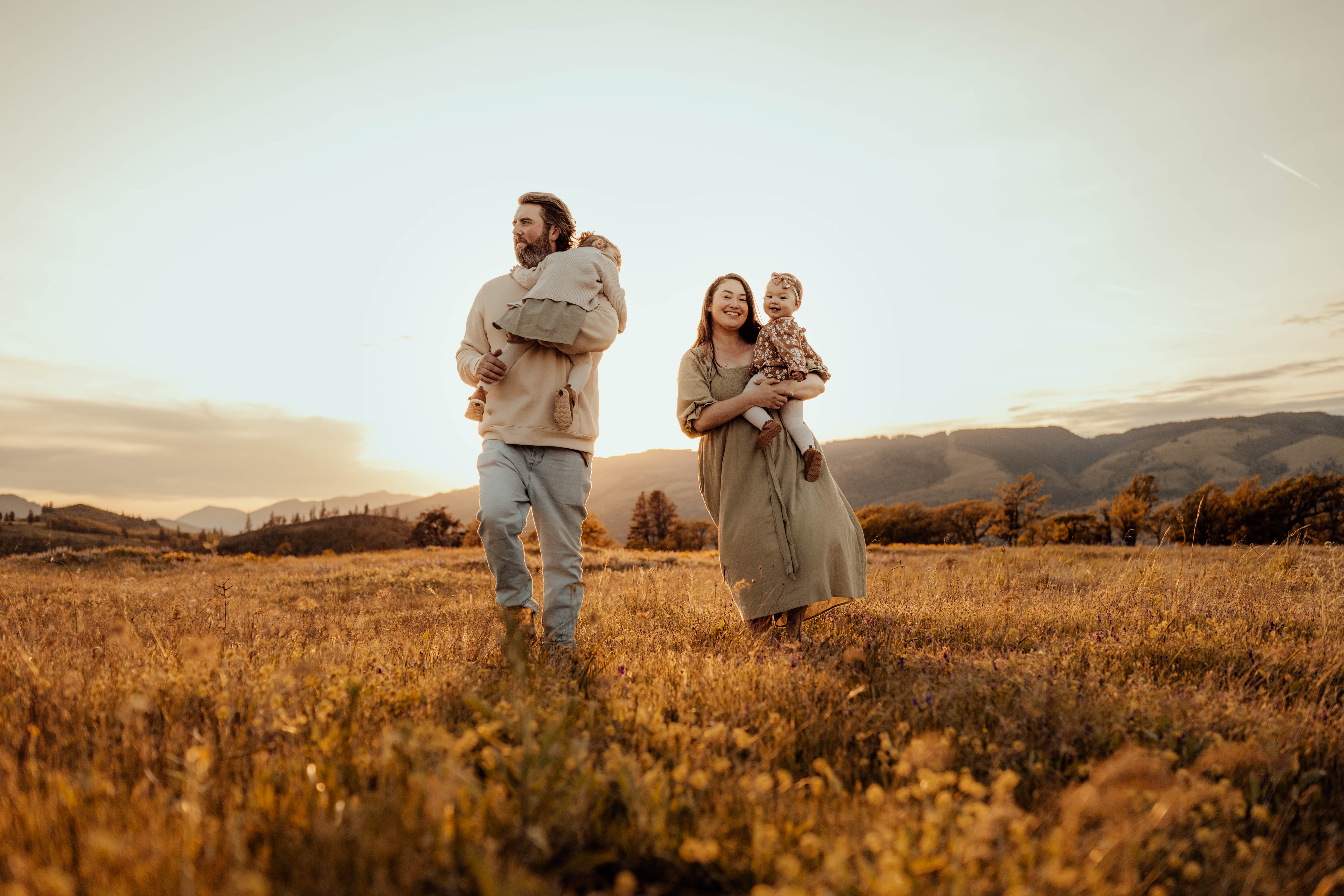 Family of four walking through a field at sunset
