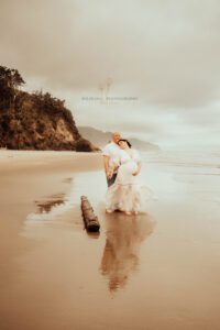 Expecting couple standing on beach at Oregon Coast