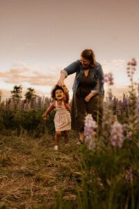 Mom twirling toddler in a field of flowers