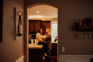 Mom and dad holing newborn in a kitchen, shot through a doorway