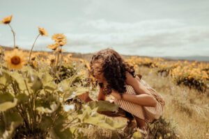 Curly hair girl in striped dress smelling the flowers