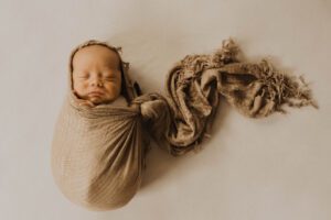 Newborn baby wrapped in brown muslin