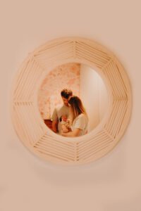 Mom, dad and newborn baby reflected in a rattan mirror