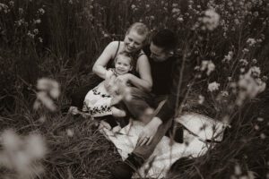 Black and white image of family snuggling in a flower field