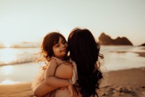 Mom and girl hugging at the ocean